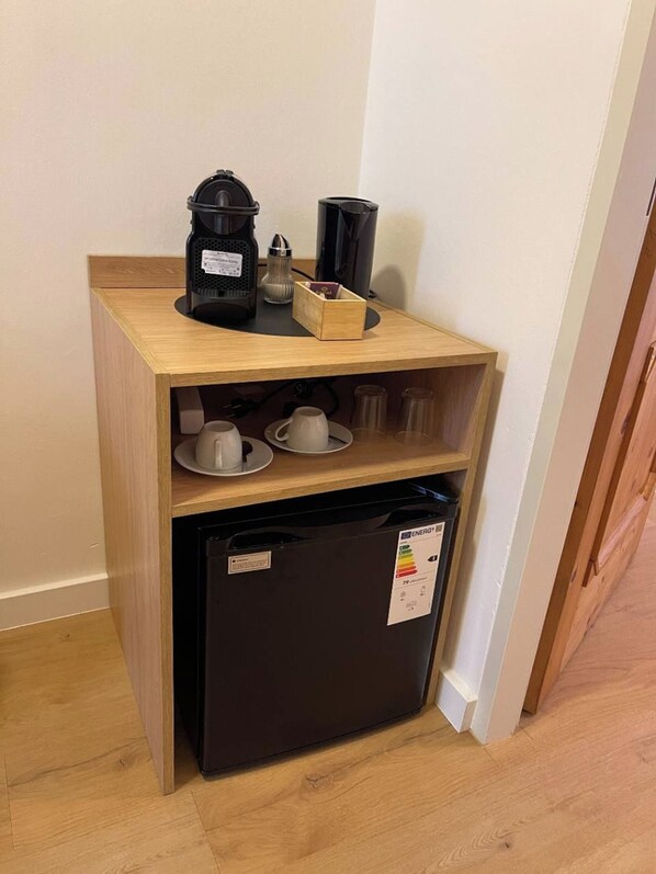 Een kleine keuken met een koffiezetapparaat, een broodrooster en een kleine koelkast.