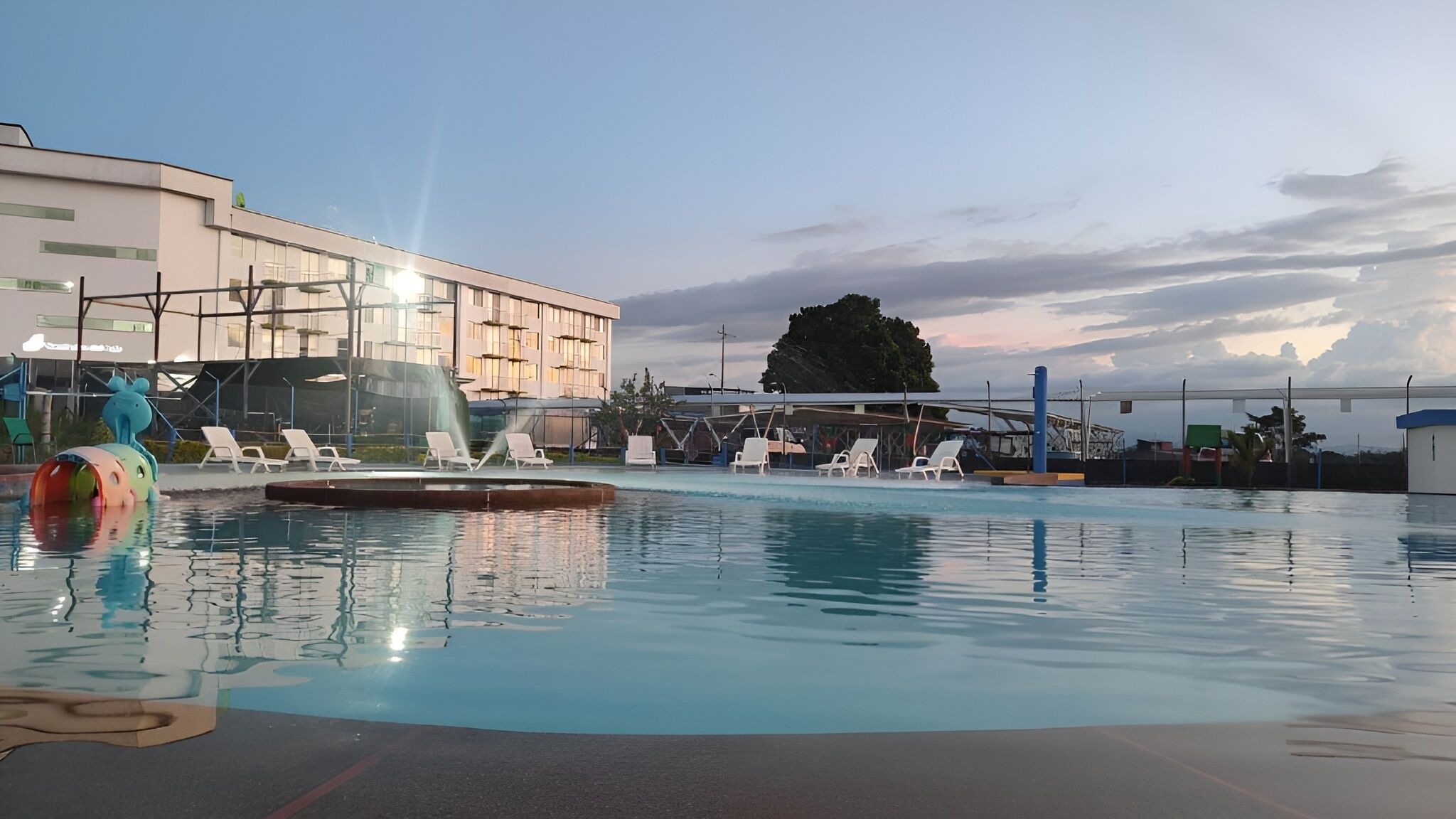 A swimming pool with lounge chairs and a water slide.