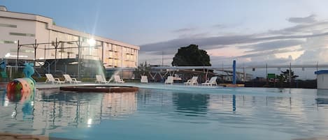 A swimming pool with lounge chairs and a water slide.