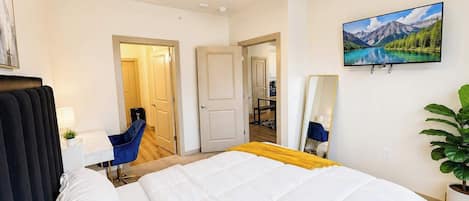 Hotellihuone, jossa on suuri sänky, kattotuuletin, seinälle asennettu televisio ja näkymä vuoristomaisemaan.
