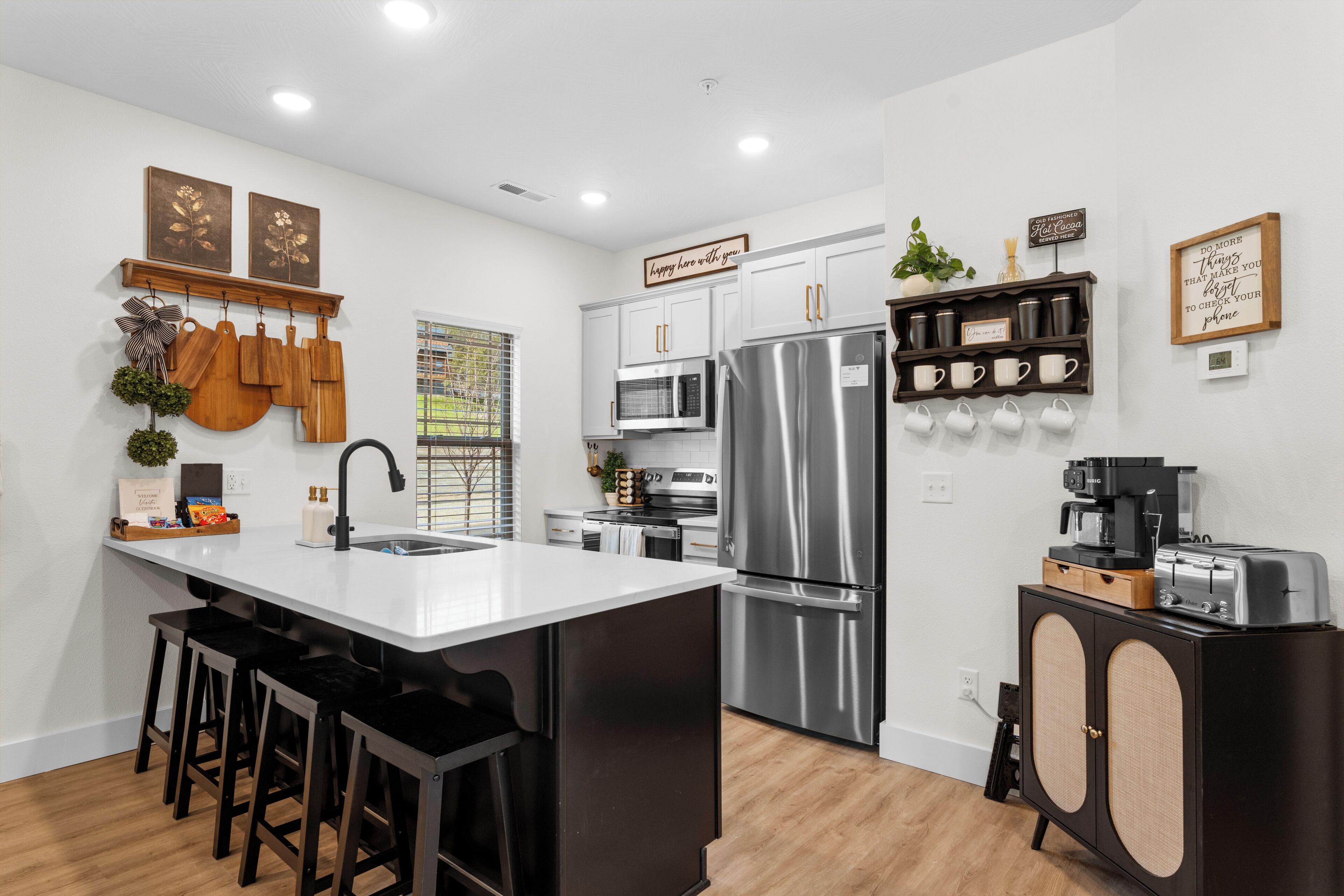 A modern kitchen with a central island, stainless steel appliances, and a coffee station.