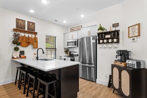 A modern kitchen with a central island, stainless steel appliances, and a coffee station. - BRAND NEW! Tall Timbers Modern Cabin w/ Hot Tub (Hollister)