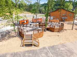 Ein rustikales Blockhaus mit einer Holzterrasse, Sitzgelegenheiten im Freien und einem Kiesweg, der zum Eingang führt.