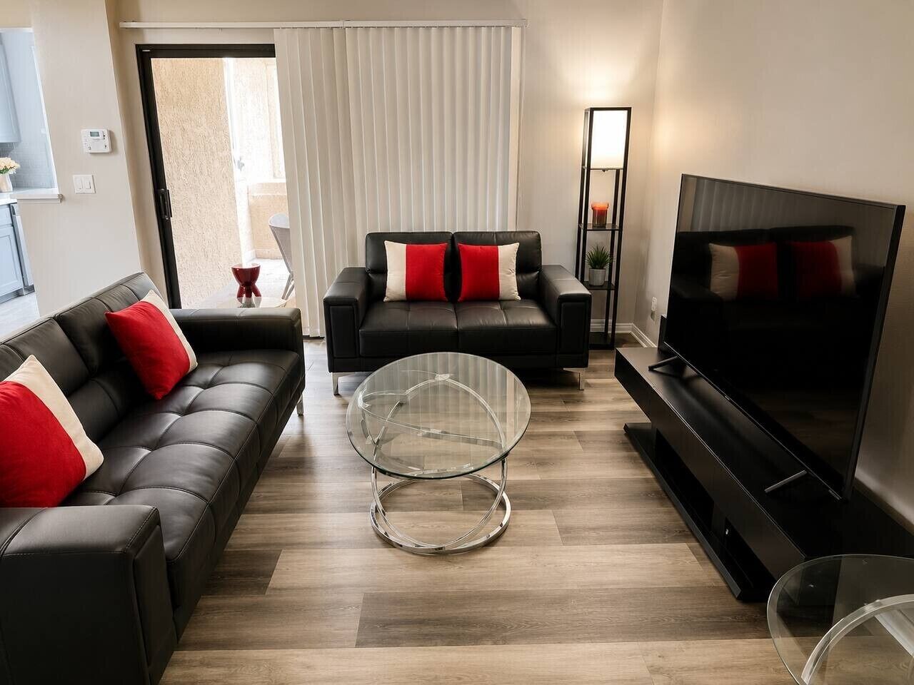 Un salon moderne comprenant un canapé, deux fauteuils, une table basse en verre, un téléviseur à écran plat et une cheminée.