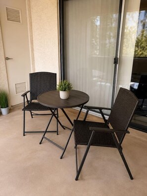A patio with a round table and two chairs, a potted plant, and a sliding glass door. - Modern 2BR Condo Near the Las Vegas Strip (Las Vegas)