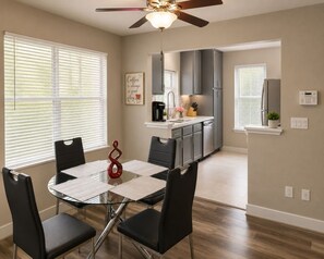 A dining area with a glass table, black chairs, and a ceiling fan. - Modern 2BR Condo Near the Las Vegas Strip (Las Vegas)