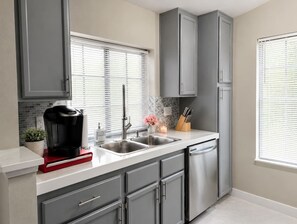 A modern kitchen with grey cabinets, a double sink, and a coffee maker on the counter. - Modern 2BR Condo Near the Las Vegas Strip (Las Vegas)