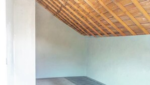 Una habitación con techo inclinado y piso de concreto.