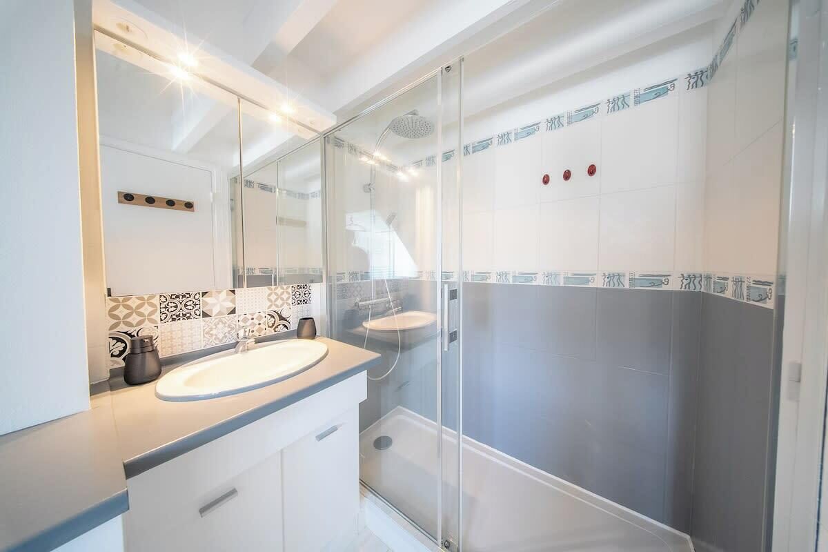 Een moderne badkamer met een douchecabine van glas, een wit wastafelmeubel en betegelde vloeren.