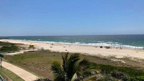 Una playa con una torre amarilla de salvavidas, una orilla de arena y cielo despejado.