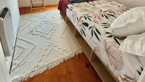 Ein Schlafzimmer mit einem Bett, einem Fenster, einer Heizung und einem gemusterten Teppich.
