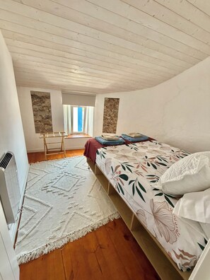 Quarto com cama, janela, radiador e tapete estampado.