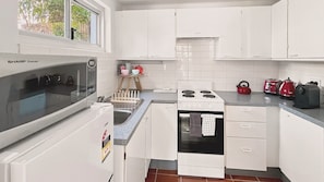 A modern kitchen with white cabinetry, a built-in oven, a stove, and a microwave. - EST11 - Balmoral Breeze | Leafy 2-Bed Duplex Garden Apartment Near the Beach (Mosman)
