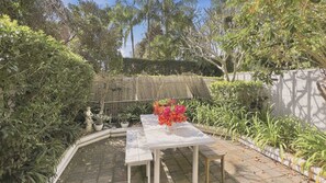 A garden with a white table and chairs, surrounded by various plants and a statue. - EST11 - Balmoral Breeze | Leafy 2-Bed Duplex Garden Apartment Near the Beach (Mosman)
