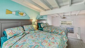 A bedroom with two beds, a ceiling fan, a fish wall art, and a window with a view. - Beachfront location, steps from the boardwalk, Fri night fireworks & more! (North Wildwood)