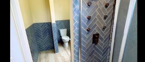 A bathroom with a herringbone-patterned wall, a toilet, and a shower area.