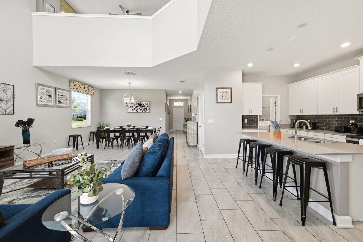 A modern kitchen with white cabinets, a black countertop, and a bar area.