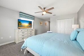 A bedroom with a bed, a ceiling fan, a dresser, a television, and a door. - Pool Home w/ Spa & Game Room · 15 Min to Disney · 5BR Sleeps 10 (Four Corners)