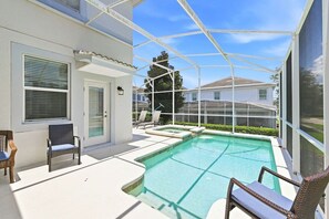 A pool area with a covered patio, outdoor seating, and a view of a residential neighborhood. - Pool Home w/ Spa & Game Room · 15 Min to Disney · 5BR Sleeps 10 (Four Corners)