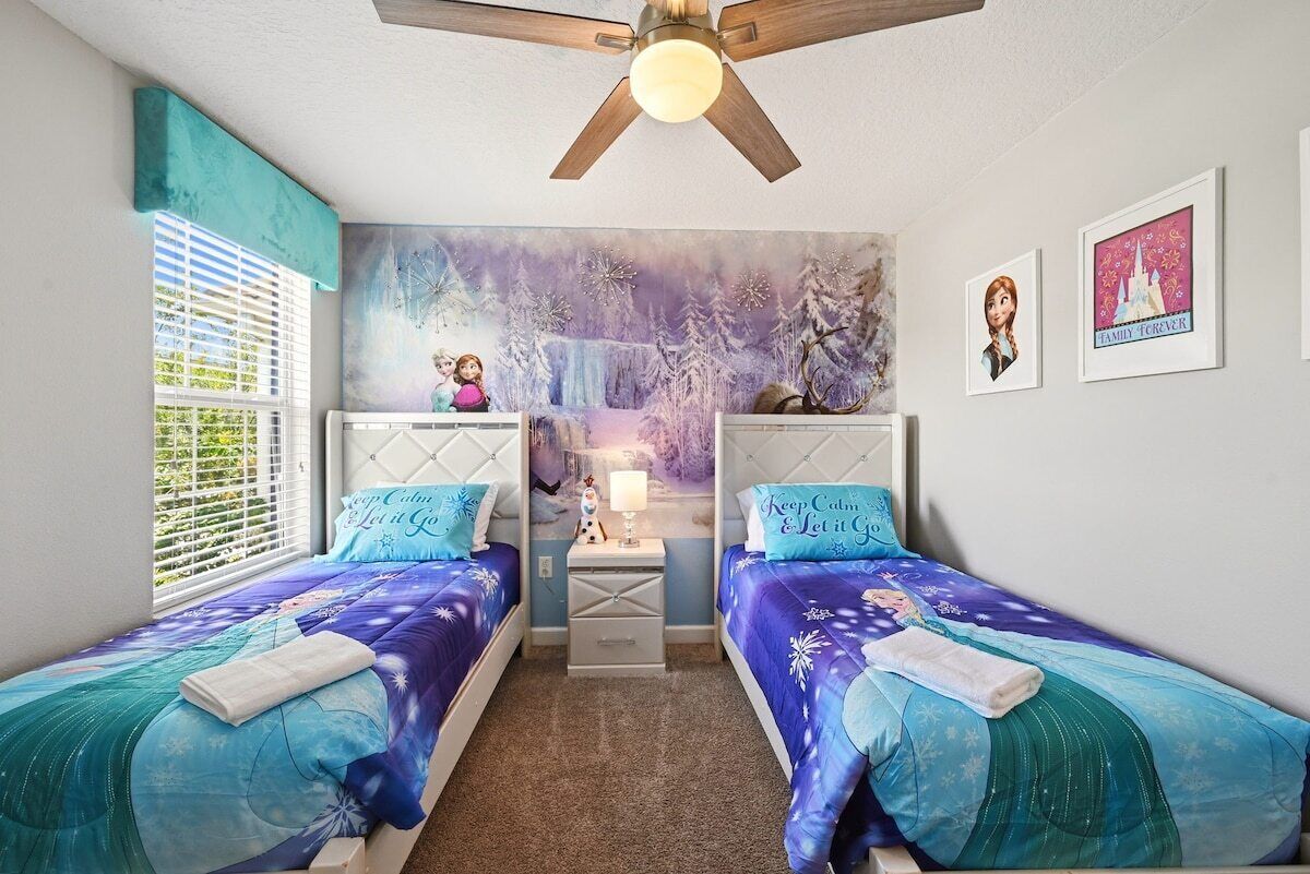 Une chambre avec deux lits, un ventilateur de plafond, une fenêtre avec des stores et une fresque murale.