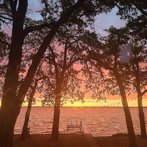 A sunset view with trees and a dock extending into a body of water. - Lakeside Retreat 4+ bedrooms 7 beds 2.5 baths (Oshkosh)