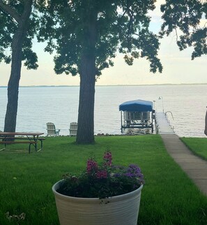 A lakeside view with a dock, picnic table, chairs, and a potted plant. - Lakeside Retreat 4+ bedrooms 7 beds 2.5 baths (Oshkosh)