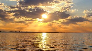 A sunset over a body of water with clouds reflecting sunlight. - Lakeside Retreat 4+ bedrooms 7 beds 2.5 baths (Oshkosh)