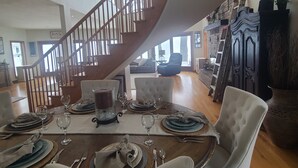 A dining area with a wooden staircase, a fireplace, and a view of the outdoors. - Lakeside Retreat 4+ bedrooms 7 beds 2.5 baths (Oshkosh)