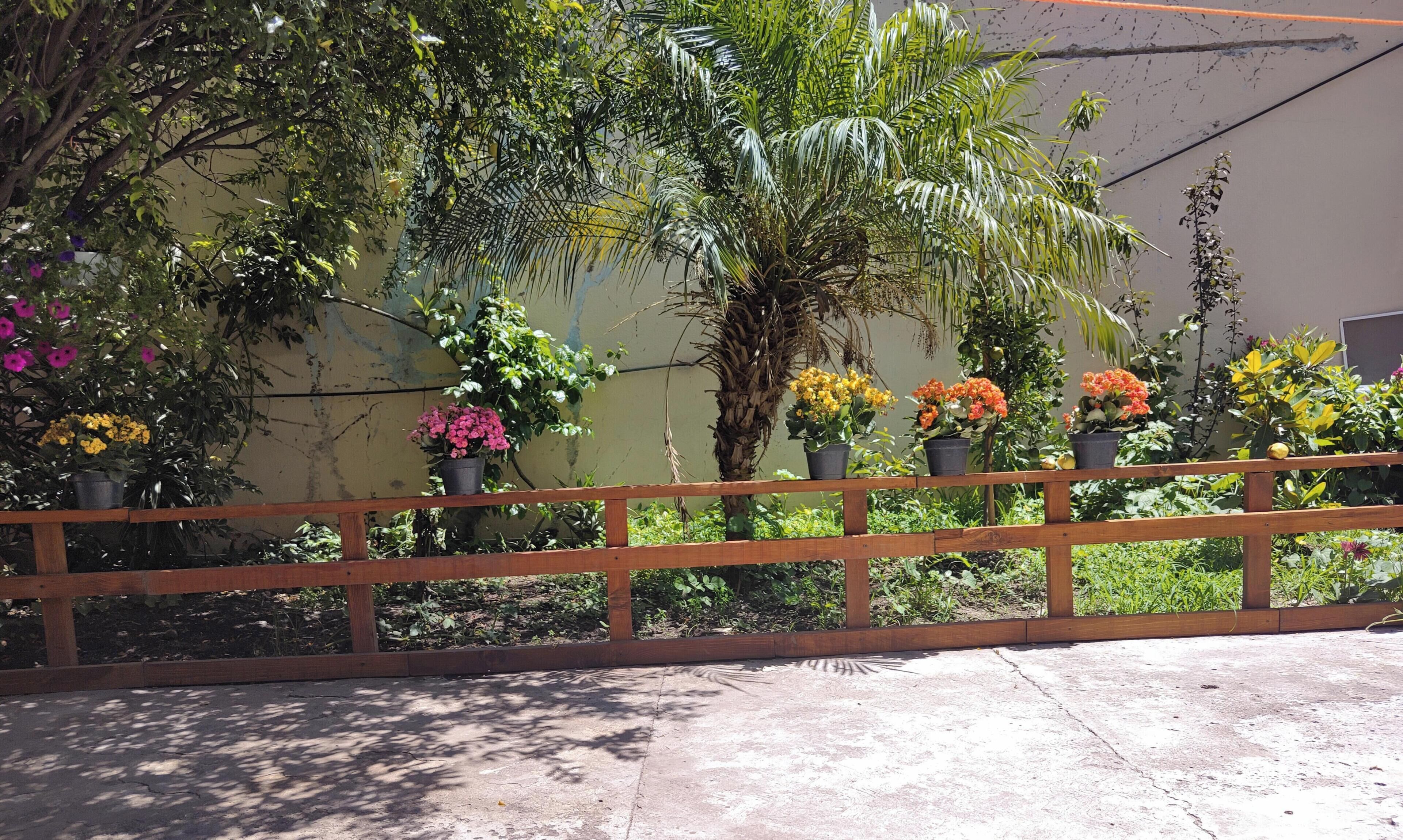 A wooden fence with potted plants and flowers.