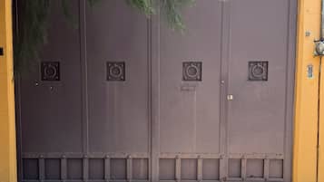 A large, closed metal gate with a circular handle, set against a yellow wall.