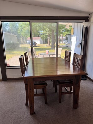 A dining area with a large wooden table and chairs, a window with a view of a residential neighborhood. - Spacious 4-bedroom house on all sports 8 Pt Lake in wonderful Lake with AC (Lake)