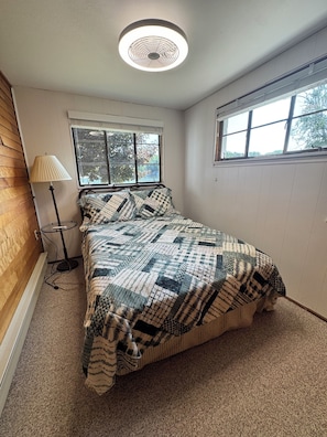 A bedroom with a bed, a standing lamp, a window, and a ceiling fan. - Spacious 4-bedroom house on all sports 8 Pt Lake in wonderful Lake with AC (Lake)