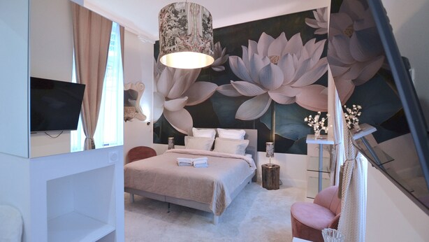 Un dormitorio moderno con una cama grande, un televisor de pantalla plana, un mural decorativo y un diseño minimalista.