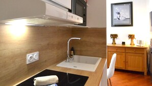 Una cocina moderna con encimera negra, pileta de acero inoxidable y un microondas arriba.