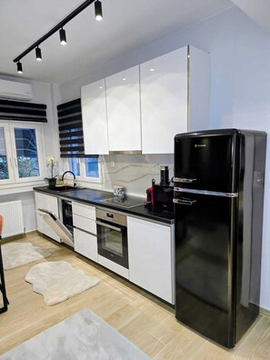 Eine moderne Küche mit weißen Schränken, einem schwarzen Kühlschrank und einem eingebauten Backofen.