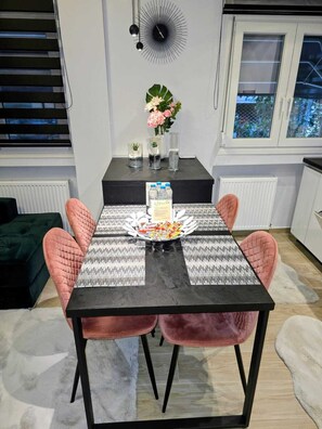 A dining area with a black table, pink chairs, a flower vase, and a clock on the wall. - Modern Luxury Apartment  Stylish & Cozy Stay (Thessaloniki)