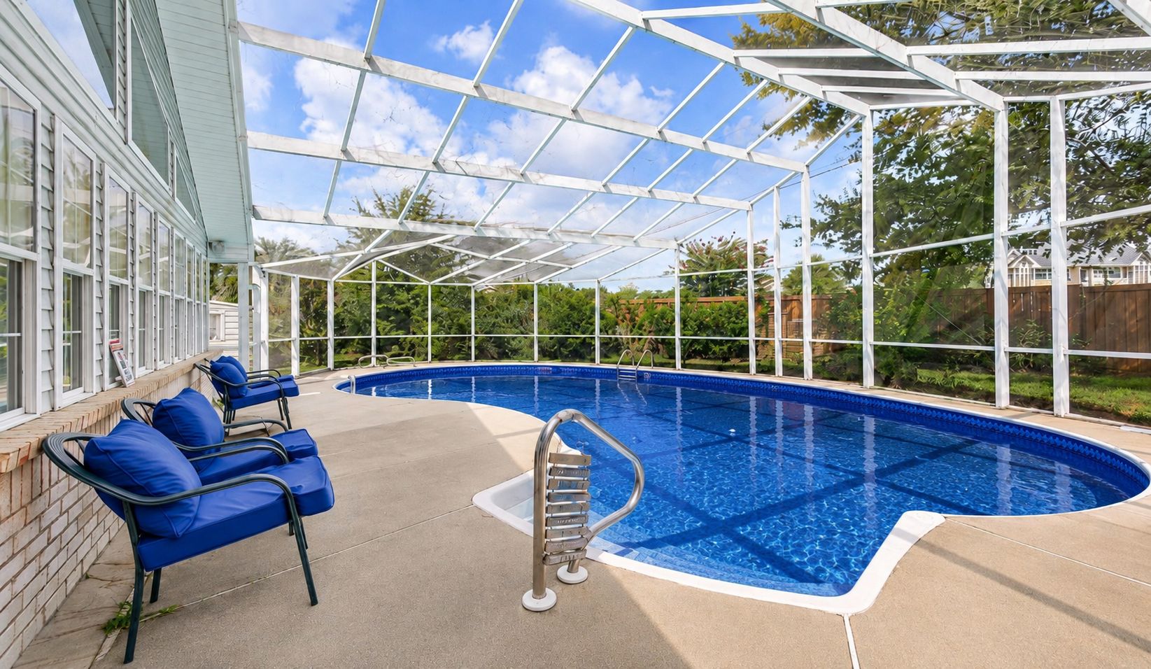 Una piscina techada con agua azul, una escalera y sillas azules.