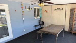 Quarto com mesa de madeira, ventoinha no teto e decoração nas paredes, incluindo peixes.