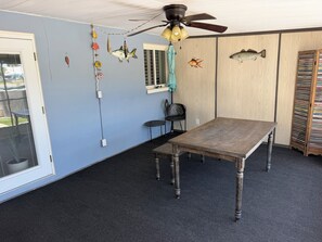 A room with a wooden table, a ceiling fan, and wall decorations including fish. - Welcoming 3-bedroom house on canal with direct gulf access (Hernando Beach)