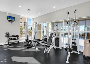 A gym with weight machines, a bench, and a fan. - NEW LISTING! | Stunning 2 BR/2BA Beachfront Condo | Crystal Shores | Gulf Shores (Gulf Shores)