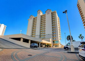 A high-rise hotel with multiple balconies, a parking garage, and a clear blue sky. - NEW LISTING! | Stunning 2 BR/2BA Beachfront Condo | Crystal Shores | Gulf Shores (Gulf Shores)