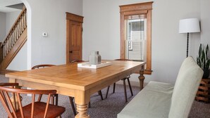 Una sala da pranzo con tavolo in legno, sedie, una panca, una pianta in vaso e una scala.