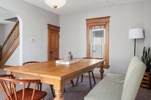 A dining room with a wooden table, chairs, a bench, a potted plant, and a staircase. - Northern Sky Cottages | 3 Houses | 8BR | 4BA | 2 Hot Tubs | Game Shed & Private Yard (Traverse City)