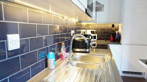 Eine moderne Küche mit Spüle aus Edelstahl, einem Wasserkocher und einer Kaffeemaschine.