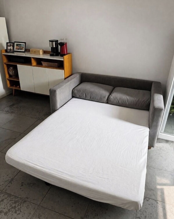 A modern room with a grey sofa bed, a white cabinet, and a coffee machine. - Studio Copanema (Rio de Janeiro)