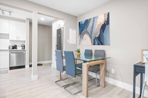 A modern kitchen with white cabinets, a stainless steel refrigerator, and a coffee maker. - Elegant Living in a 1-Bedroom Suite (Edmonton)