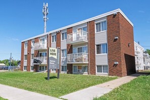 A multi-story apartment building with balconies, a sign advertising available apartments, and a clear blue sky. - Elegant Living in a 1-Bedroom Suite (Edmonton)