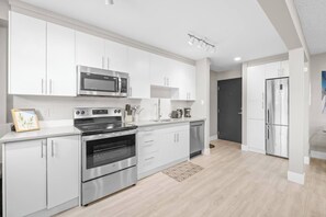 Eine moderne Küche mit Edelstahlgeräten, weißen Schränken und Holzboden.