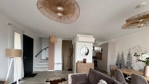 A modern living room with a sofa, a coffee table, and a dining area with a wooden table and chairs. - Chalet Altéa - 7 à 8 pers - Neuf & Cosy - 300 m des Pistes (Risoul)