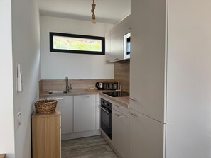 Eine kompakte Küche mit Backofen, Spüle und Mikrowelle.